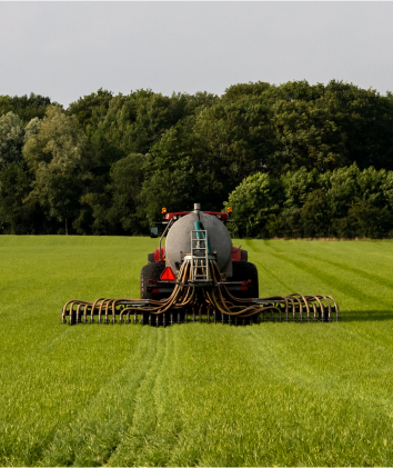 plano por atrás de un tipo de transporte utilizando fertilizantes en un campo. atrá del propio camión tiene como una especie de tubos para regar o echar fertilizante