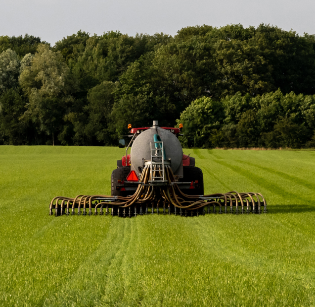 plano por atrás de un tipo de transporte utilizando fertilizantes en un campo. atrá del propio camión tiene como una especie de tubos para regar o echar fertilizante